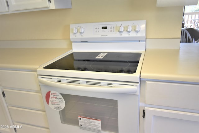 details featuring light countertops, white range with electric stovetop, and white cabinets