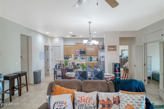 living room with light tile patterned flooring and ceiling fan with notable chandelier