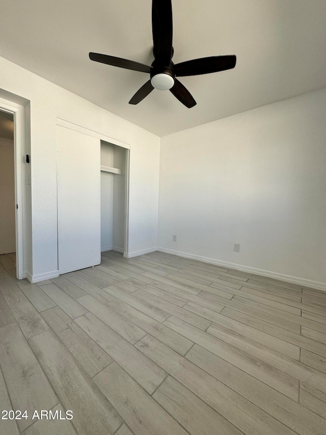 unfurnished bedroom with ceiling fan, a closet, and light hardwood / wood-style flooring