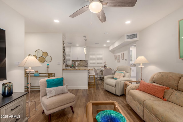 living room with light hardwood / wood-style flooring and ceiling fan