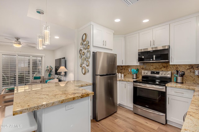 kitchen with white cabinets, decorative backsplash, light hardwood / wood-style flooring, and appliances with stainless steel finishes