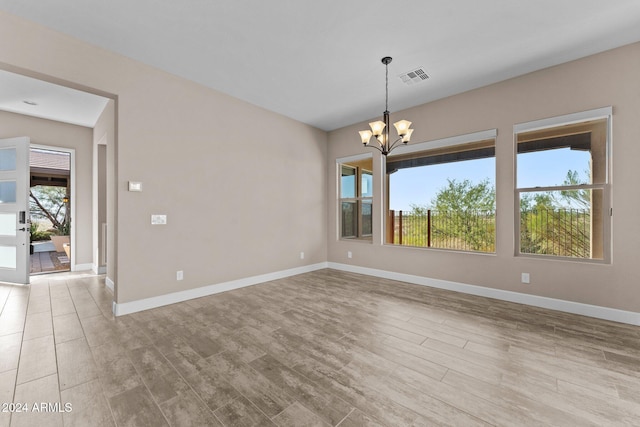 spare room with a chandelier and light hardwood / wood-style floors