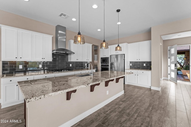 kitchen with hanging light fixtures, sink, wall chimney exhaust hood, appliances with stainless steel finishes, and a large island