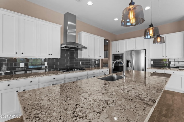 kitchen with sink, wall chimney exhaust hood, an island with sink, and appliances with stainless steel finishes