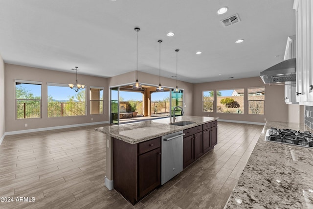 kitchen with a chandelier, appliances with stainless steel finishes, a wealth of natural light, and dark brown cabinets