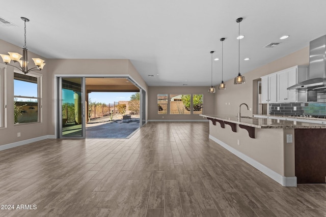 kitchen with white cabinetry, tasteful backsplash, dark stone counters, decorative light fixtures, and a breakfast bar