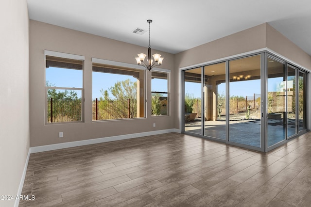 unfurnished room with wood-type flooring and a notable chandelier