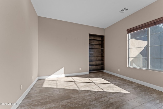 unfurnished room featuring built in shelves