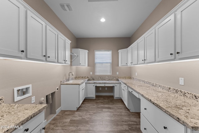 kitchen with white cabinets, light stone counters, sink, and light hardwood / wood-style flooring