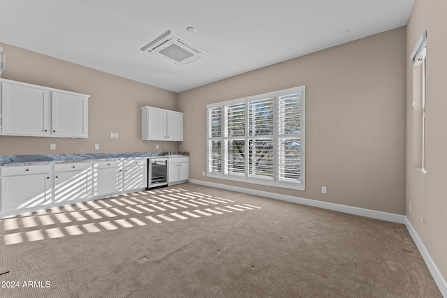 kitchen featuring white cabinetry, sink, light stone countertops, wine cooler, and light colored carpet