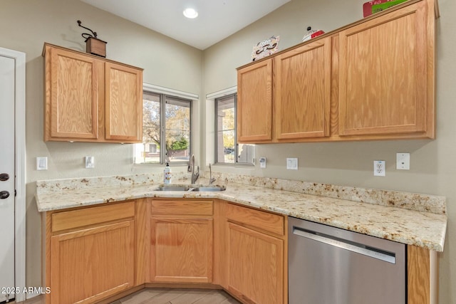 kitchen with light stone countertops, light brown cabinetry, stainless steel dishwasher, and sink