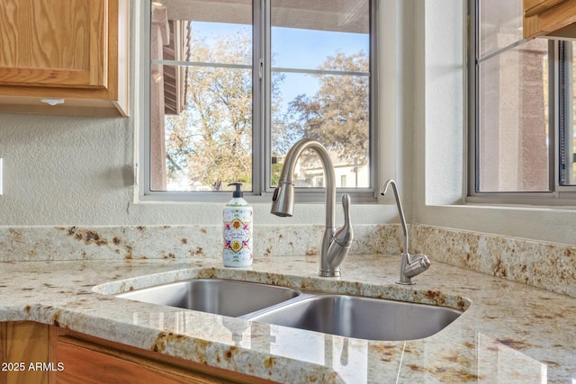 interior details featuring light stone countertops and sink