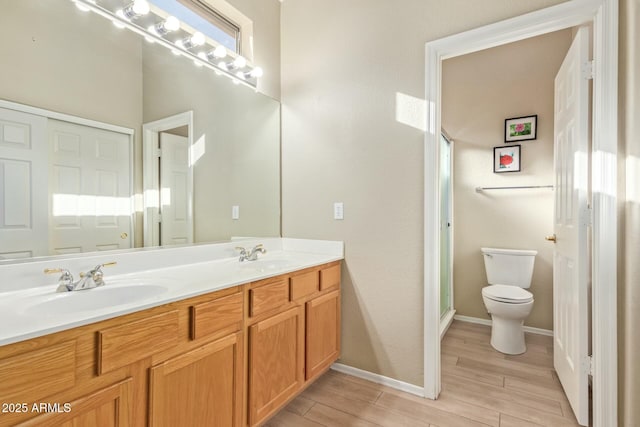 bathroom featuring hardwood / wood-style flooring, a shower with door, vanity, and toilet