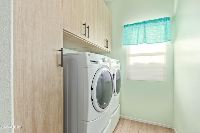 clothes washing area with cabinets, separate washer and dryer, and light hardwood / wood-style flooring