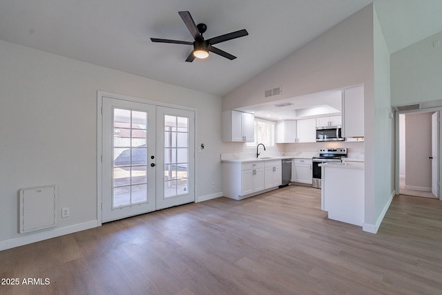 kitchen featuring lofted ceiling, sink, white cabinetry, stainless steel appliances, and french doors