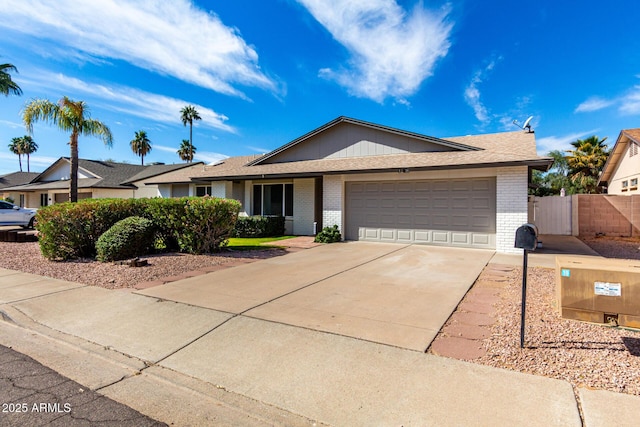 single story home with brick siding, concrete driveway, a garage, and fence