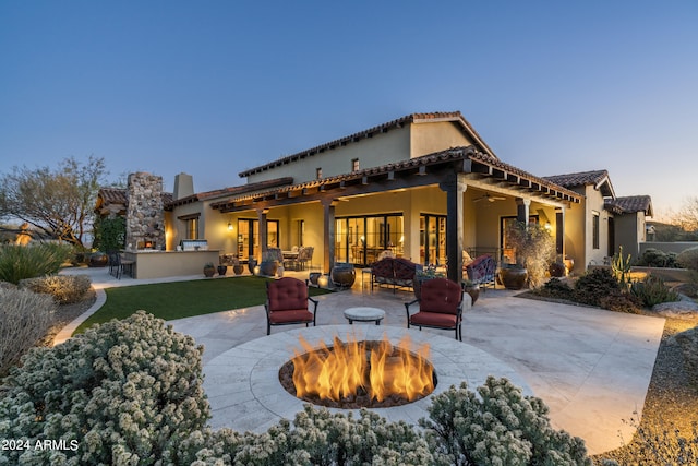 back house at dusk with a patio, ceiling fan, and an outdoor fire pit