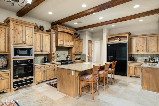 kitchen with beam ceiling, decorative backsplash, black appliances, and a center island with sink