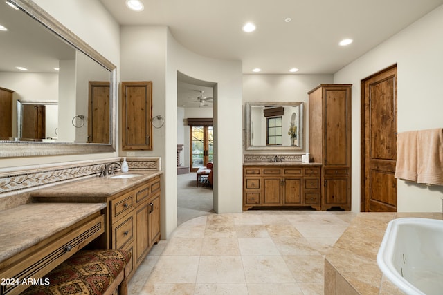 bathroom with tiled tub, vanity, and ceiling fan