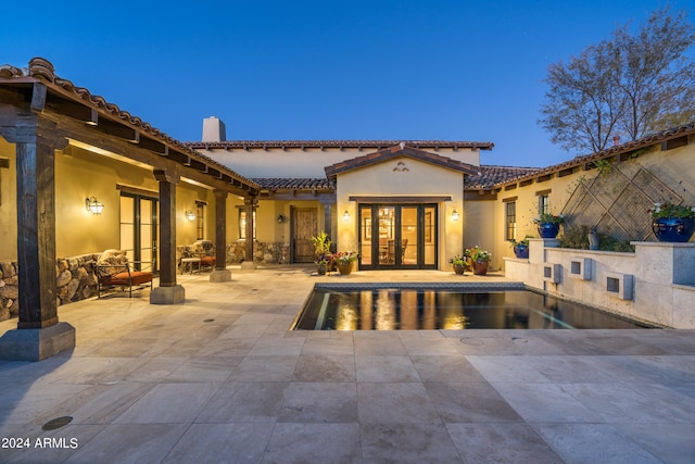 pool at dusk featuring a patio area and french doors