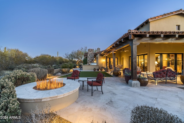 patio terrace at dusk with ceiling fan and an outdoor living space with a fire pit