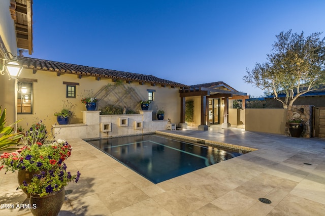 pool at dusk featuring a patio area