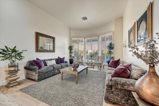 living room featuring visible vents, baseboards, and wood finished floors