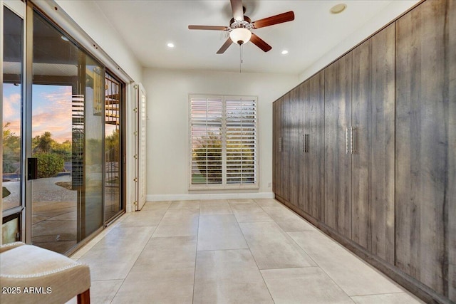 unfurnished room featuring a ceiling fan, light tile patterned floors, a healthy amount of sunlight, and baseboards