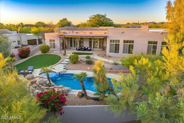 rear view of property featuring a patio area, stucco siding, an outdoor pool, and a fenced backyard