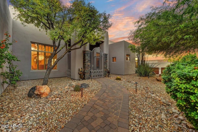 view of front of house featuring stucco siding and a gate