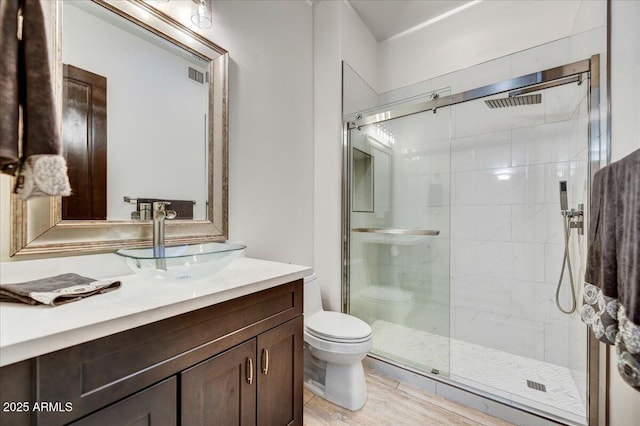 full bath with visible vents, toilet, wood finished floors, a shower stall, and vanity