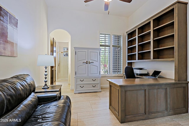 office area with arched walkways and ceiling fan