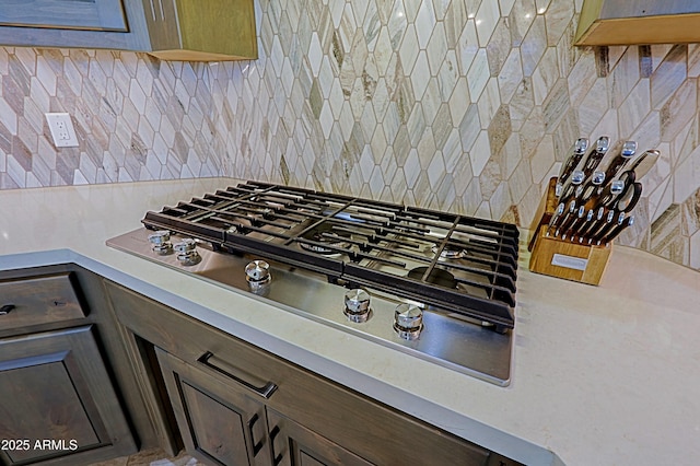 details with tasteful backsplash, light countertops, and stainless steel gas stovetop