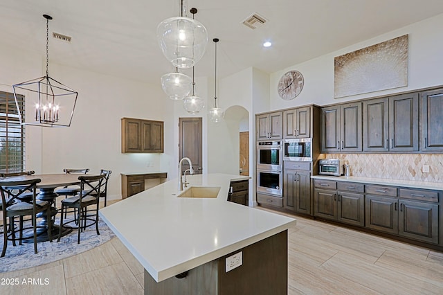 kitchen featuring visible vents, light countertops, arched walkways, stainless steel appliances, and a sink