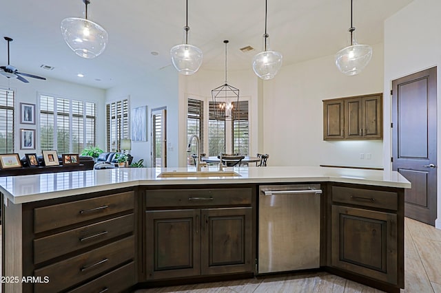 kitchen with visible vents, a sink, hanging light fixtures, light countertops, and dark brown cabinets