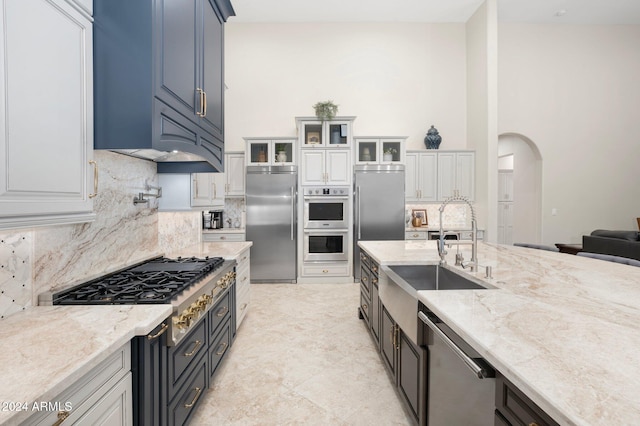 kitchen featuring white cabinets, appliances with stainless steel finishes, decorative backsplash, and light stone countertops