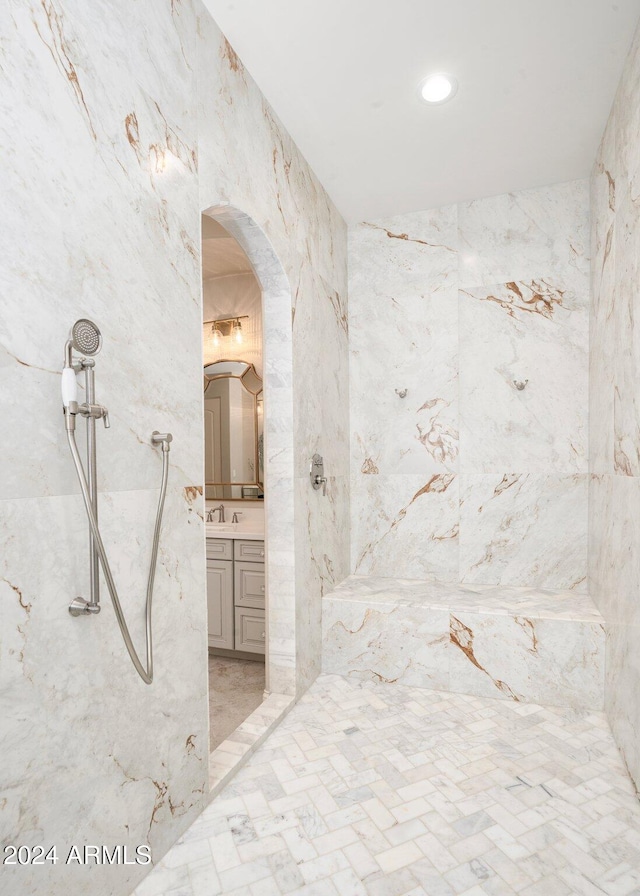 bathroom with vanity, tiled shower, and tile walls