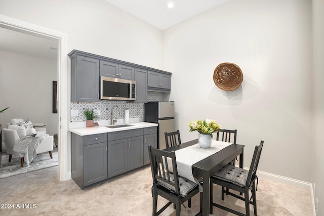 kitchen featuring backsplash, stainless steel appliances, gray cabinetry, and sink