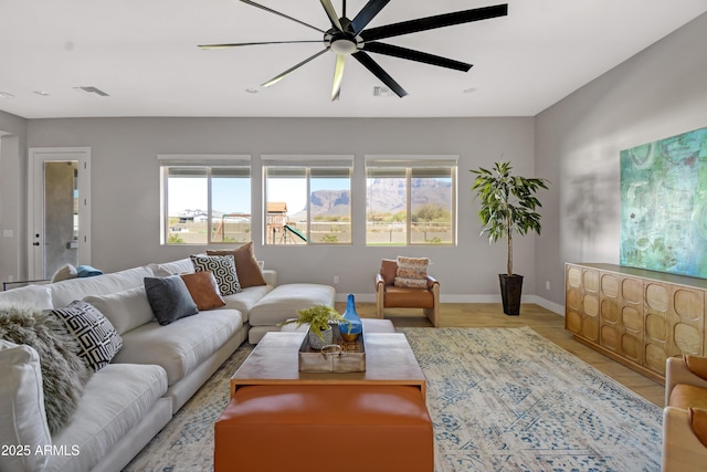 living area with visible vents, ceiling fan, baseboards, and wood finished floors