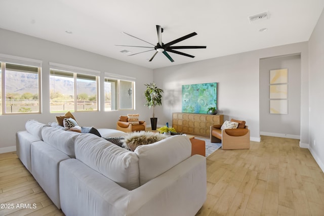 living area with a ceiling fan, baseboards, visible vents, and light wood finished floors