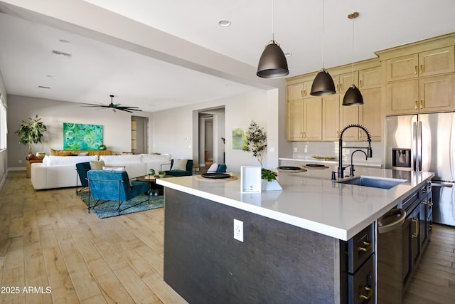 kitchen with light wood-style floors, light countertops, stainless steel fridge, and a sink