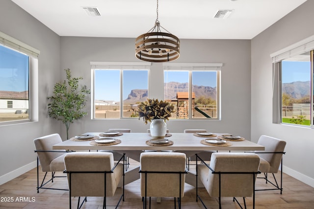 dining space featuring visible vents, light wood-type flooring, a wealth of natural light, and baseboards