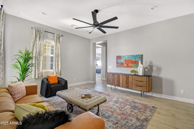 living area with ceiling fan, wood finished floors, visible vents, and baseboards