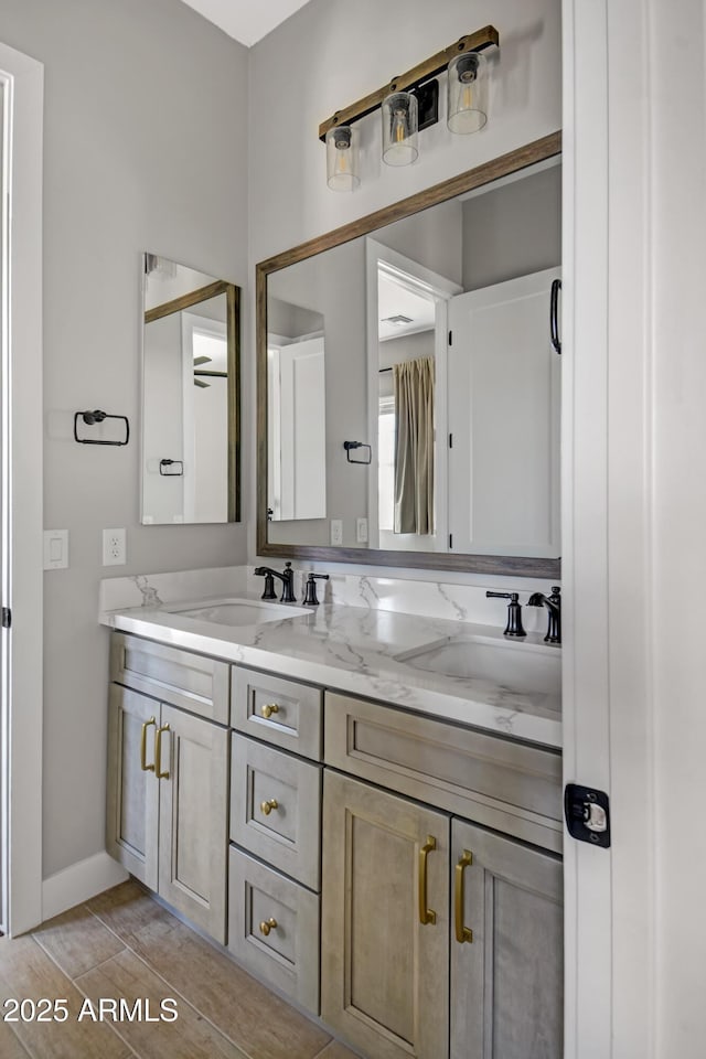 bathroom featuring double vanity, a sink, and baseboards