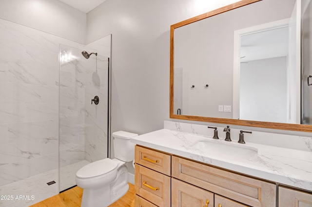 bathroom with vanity, wood finished floors, a marble finish shower, and toilet