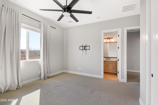 unfurnished bedroom with light carpet, ensuite bathroom, visible vents, and baseboards