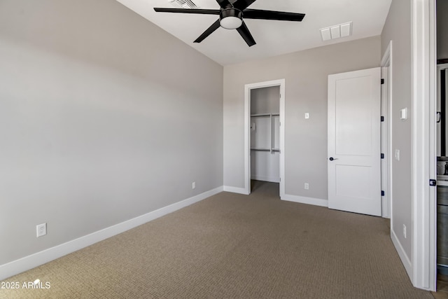 unfurnished bedroom featuring a spacious closet, dark carpet, visible vents, and baseboards