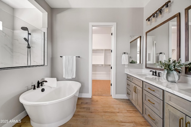 full bathroom featuring wood finished floors, vanity, baseboards, a freestanding bath, and walk in shower