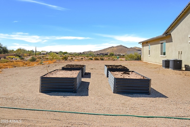 view of yard featuring central AC unit, a garden, and a mountain view