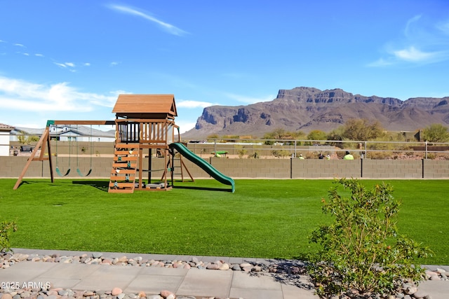 view of play area featuring fence, a mountain view, and a yard